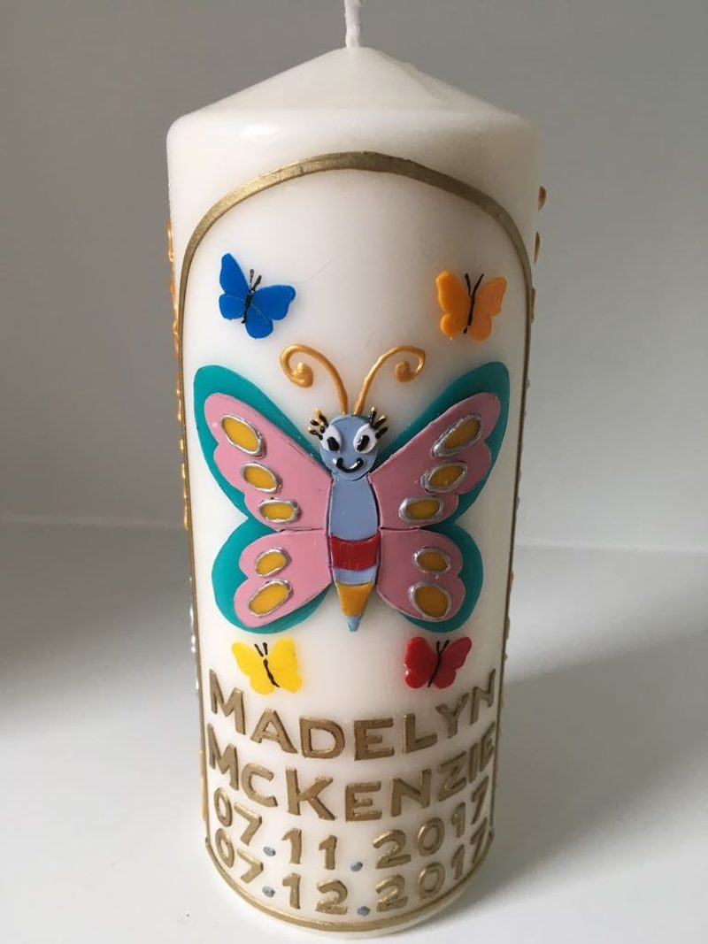 Candle for Madelyn McKenzie decorated with a smiling pink and blue butterfly